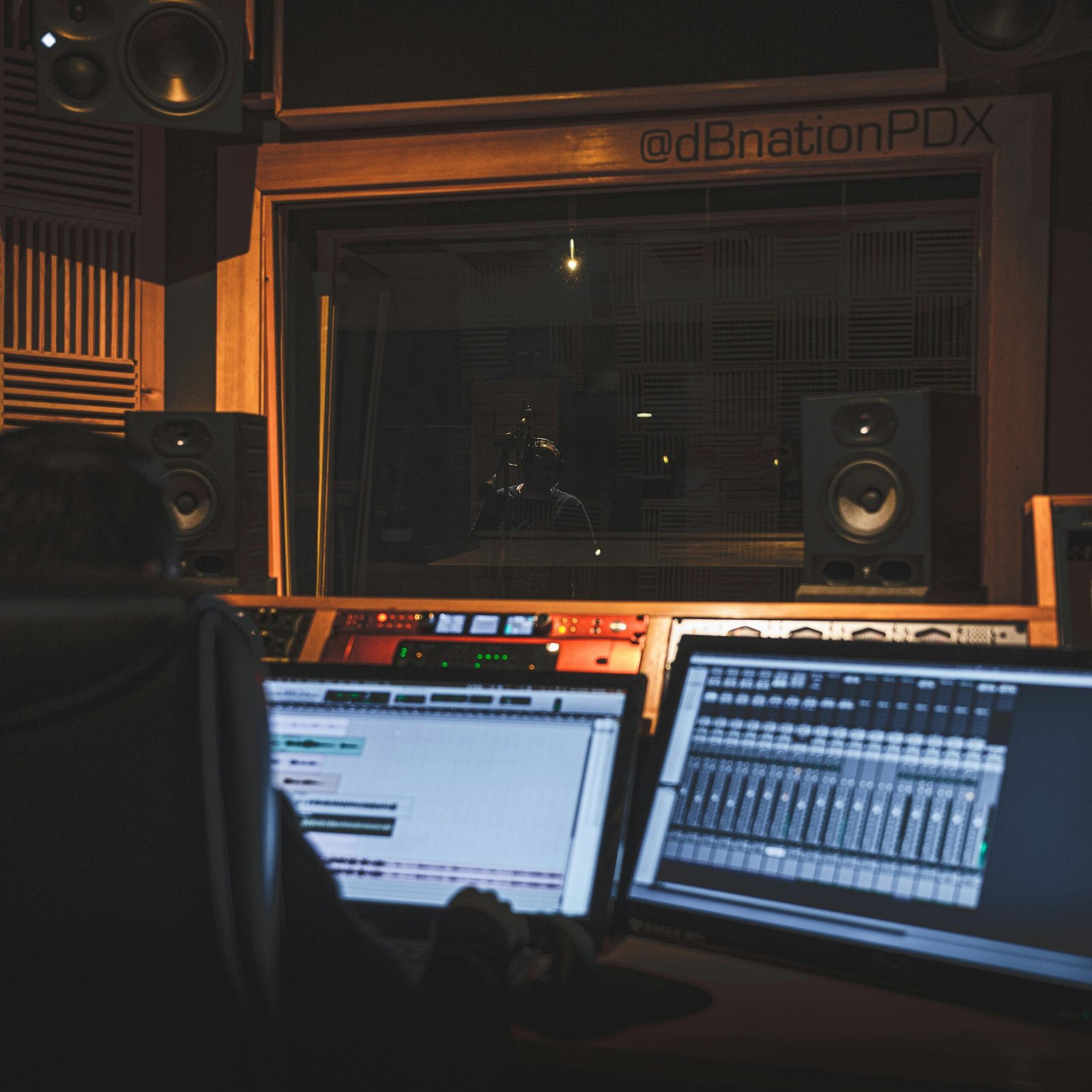 A modern music studio featuring a professional engineer at the mixing desk during a recording session.